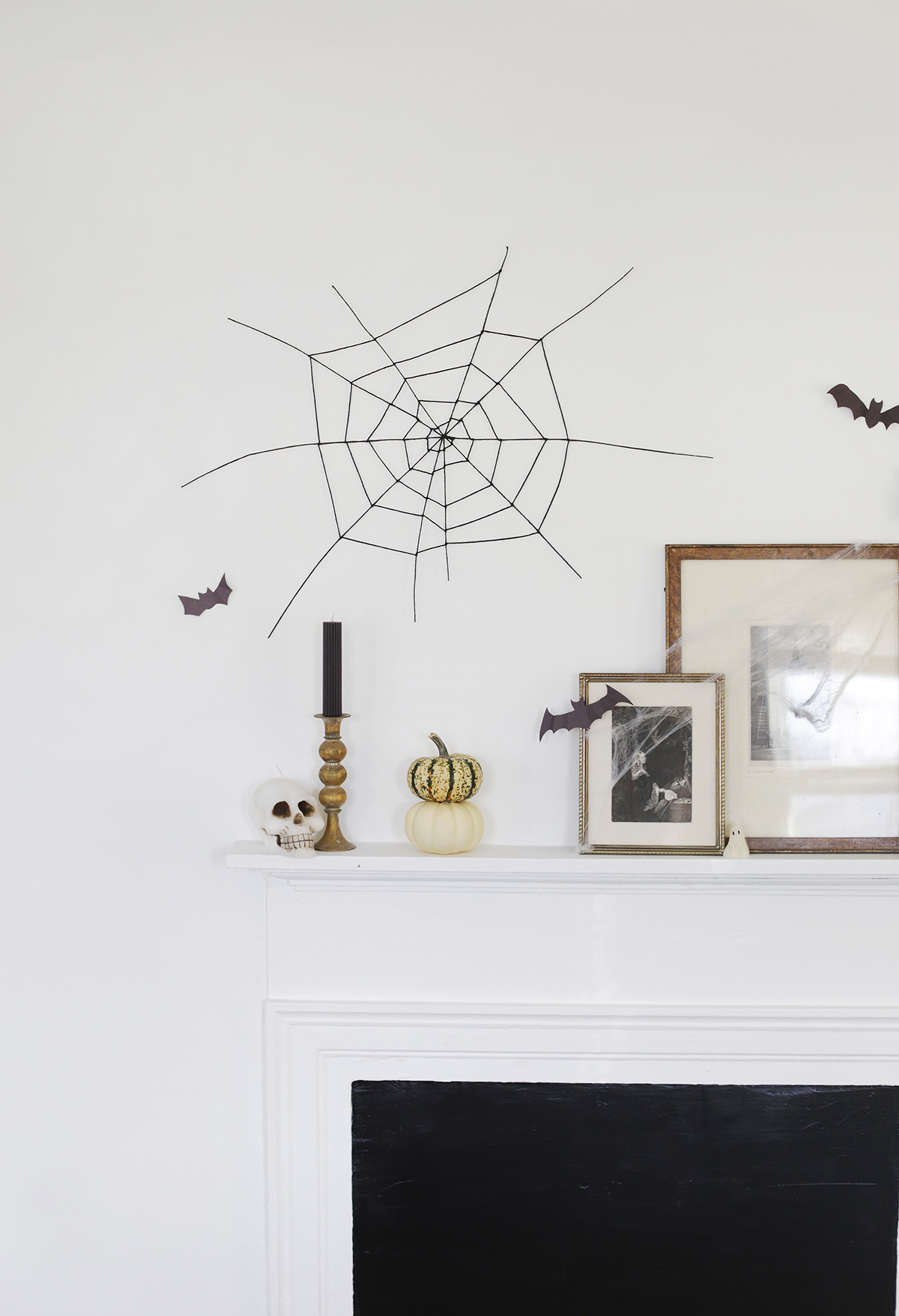 black spider web decor hanging on white wall above mantel